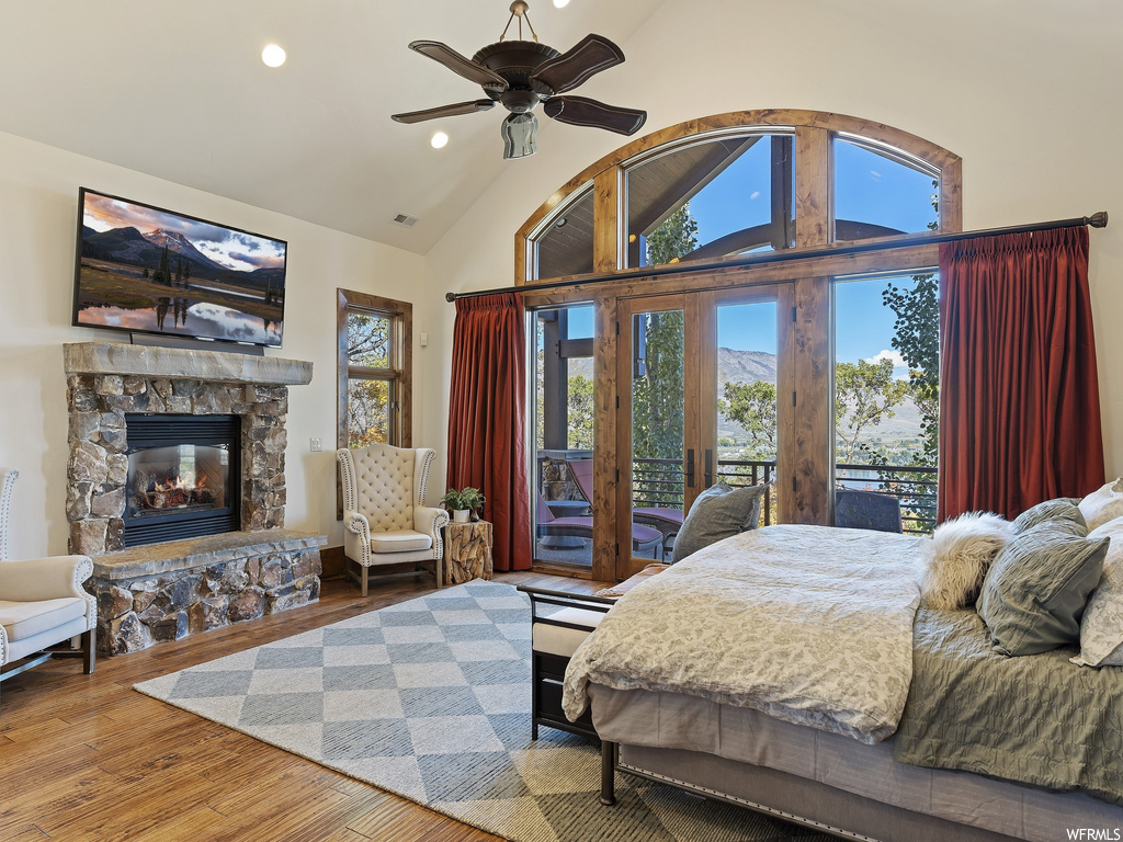 Bedroom with high vaulted ceiling, multiple windows, a fireplace, and access to exterior