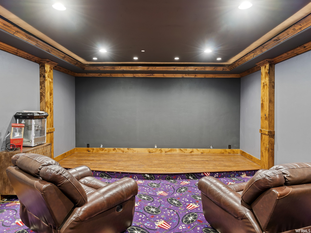 Home theater room with a tray ceiling and ornamental molding