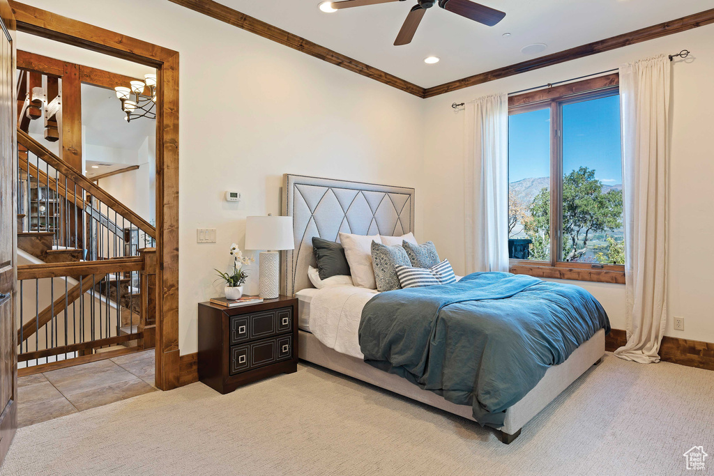 Tiled bedroom with ornamental molding, multiple windows, and ceiling fan with notable chandelier