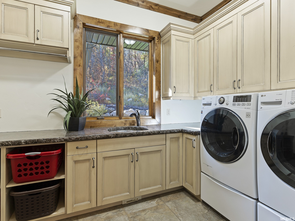 Laundry area with cabinets, washing machine and dryer, light tile floors, and sink