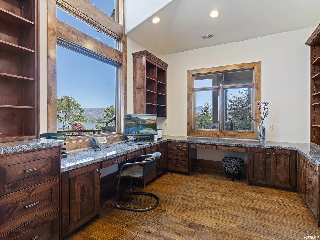 Home office featuring built in desk, dark hardwood / wood-style floors, and a healthy amount of sunlight
