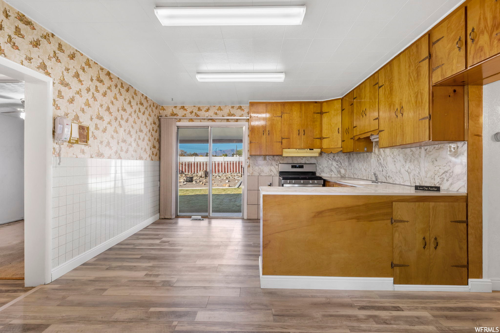 Kitchen featuring light hardwood / wood-style floors, tasteful backsplash, and stainless steel range oven