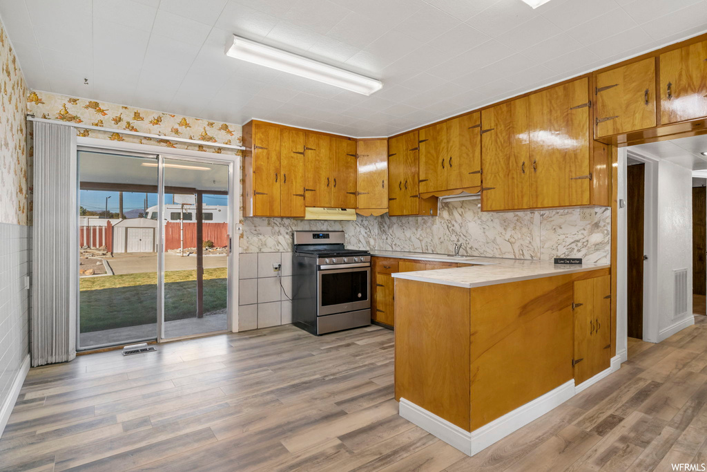 Kitchen featuring light hardwood / wood-style floors, tasteful backsplash, and stainless steel range