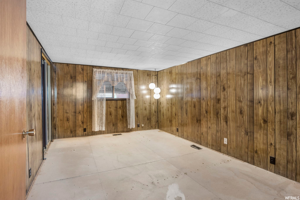Unfurnished room featuring wood walls
