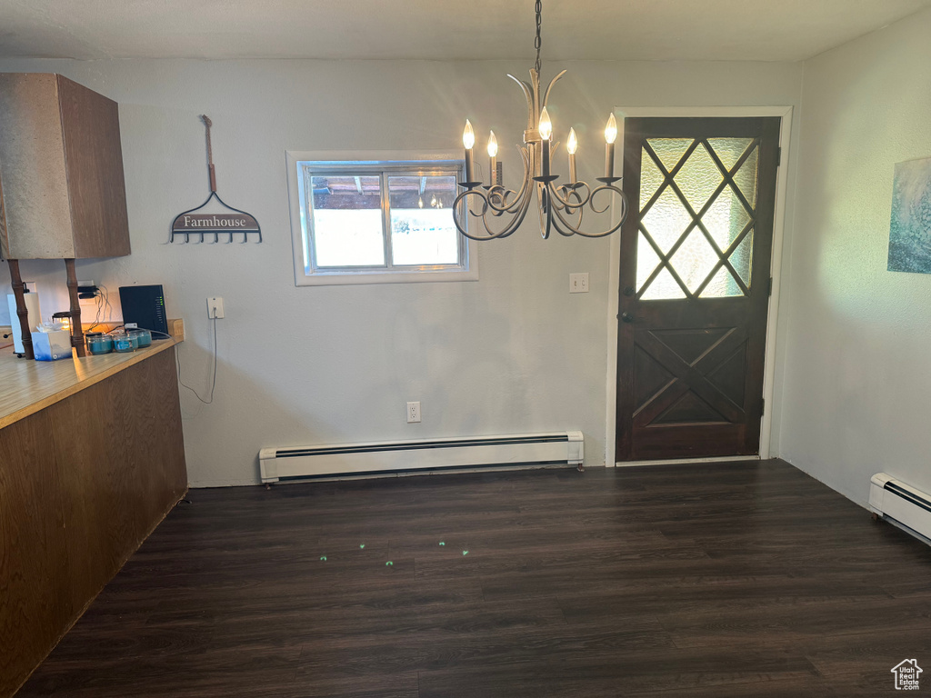 Interior space featuring dark wood-type flooring, baseboard heating, and a chandelier