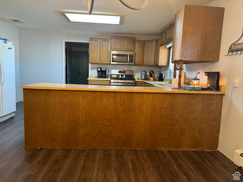 Kitchen featuring kitchen peninsula, dark hardwood / wood-style flooring, white fridge, and range