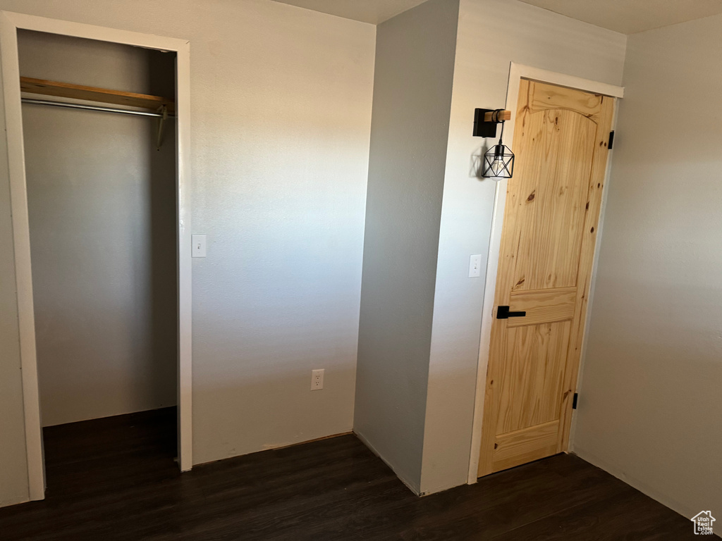 Unfurnished bedroom featuring dark hardwood / wood-style floors and a closet