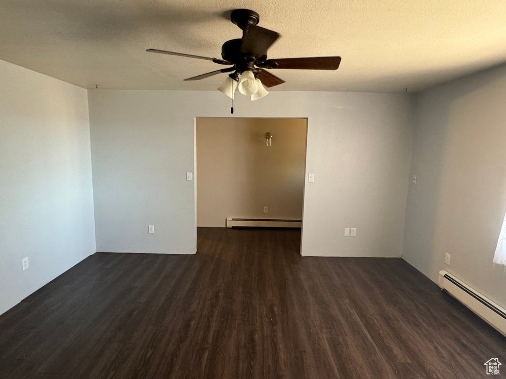 Unfurnished room with baseboard heating, dark hardwood / wood-style floors, and ceiling fan