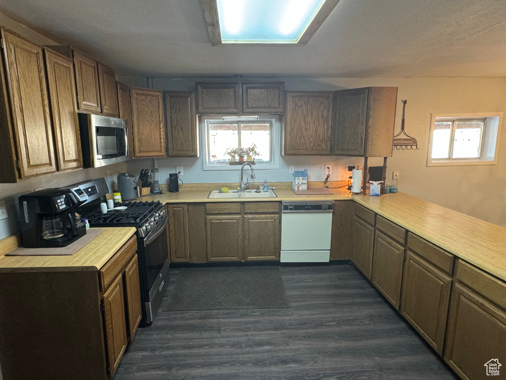 Kitchen featuring dark hardwood / wood-style flooring, range with gas cooktop, dishwasher, and sink