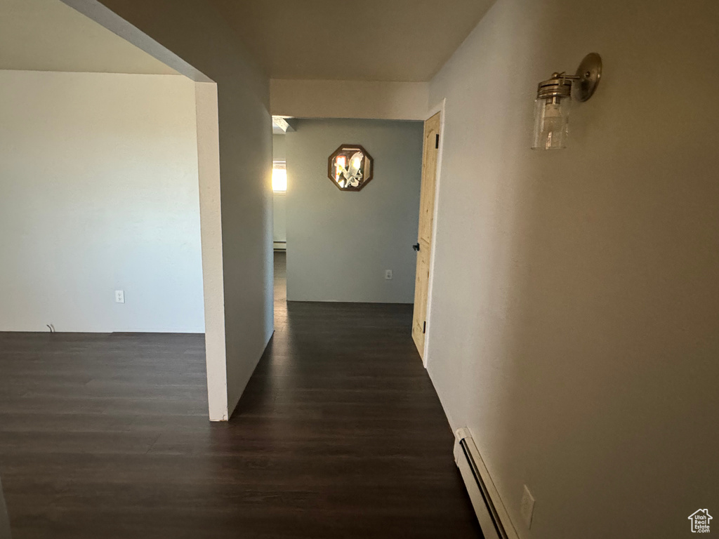 Corridor with a baseboard radiator and dark hardwood / wood-style flooring