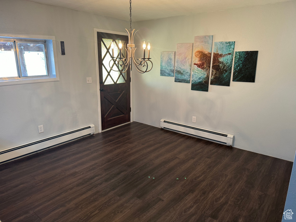 Unfurnished dining area with a baseboard radiator, a chandelier, and dark wood-type flooring