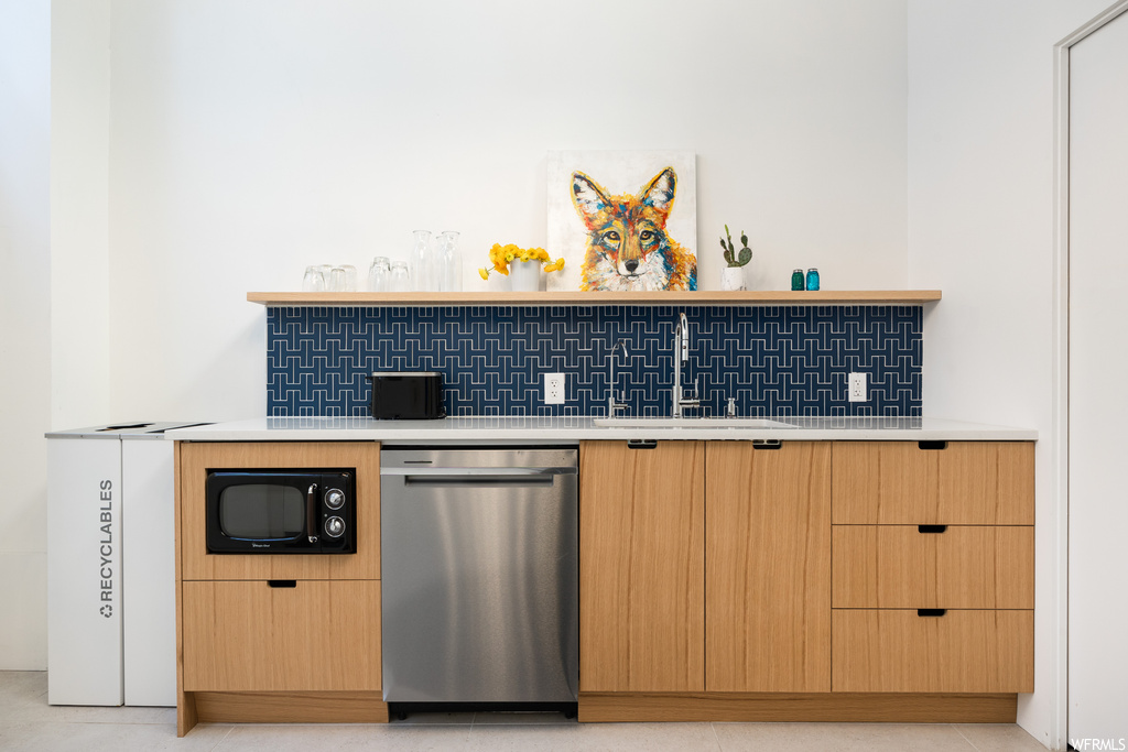 Kitchen featuring sink, backsplash, dishwasher, and light tile floors