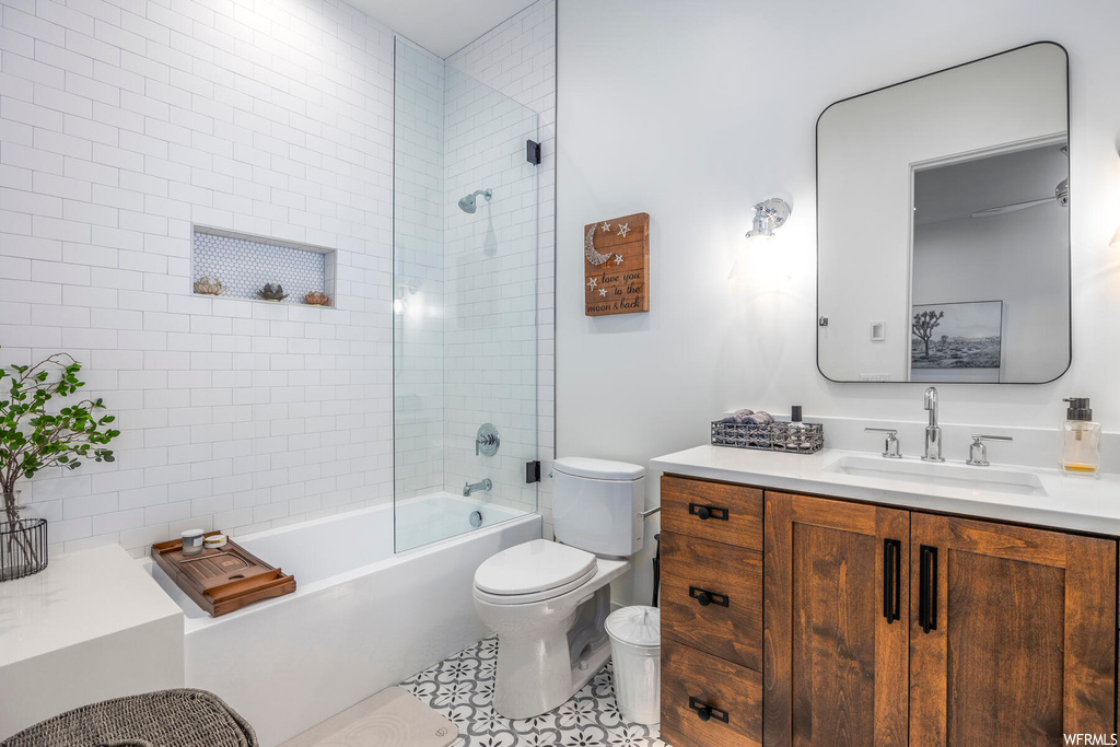 Full bathroom featuring tile floors, toilet, bath / shower combo with glass door, and oversized vanity