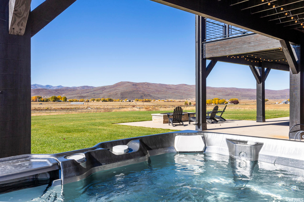 View of pool featuring a hot tub, a mountain view, and a patio
