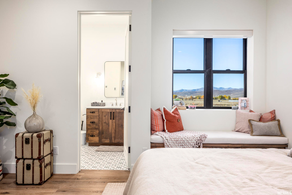 Bedroom featuring ensuite bath, radiator heating unit, and light hardwood / wood-style flooring