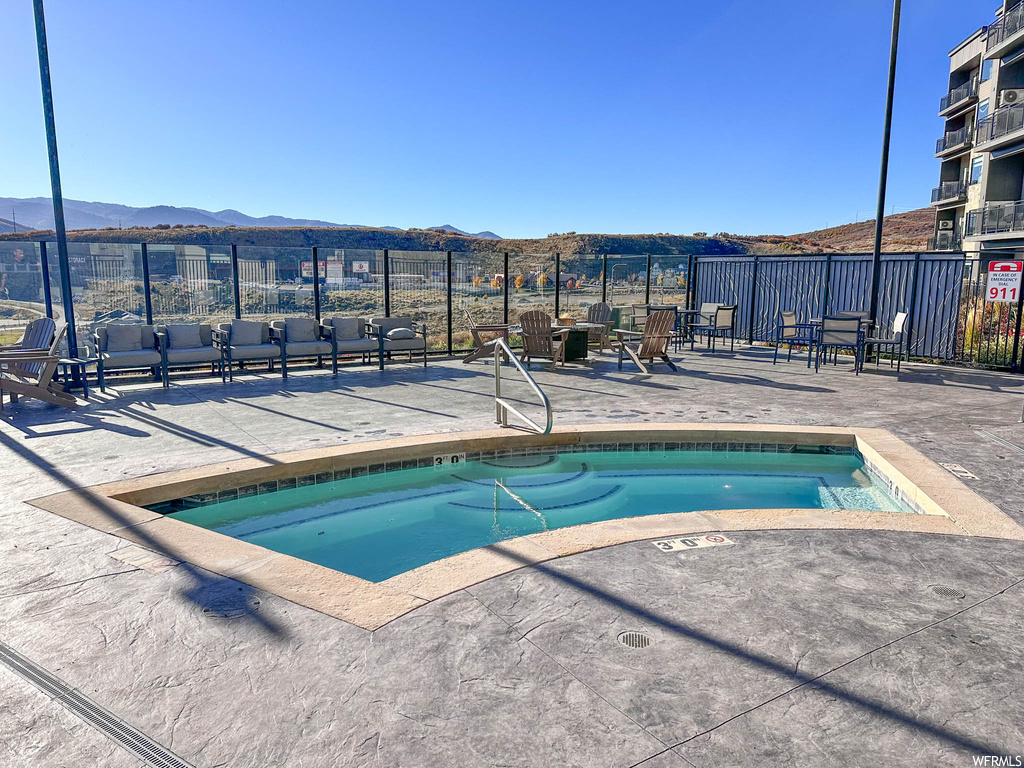 View of swimming pool featuring a hot tub, a patio, and a mountain view