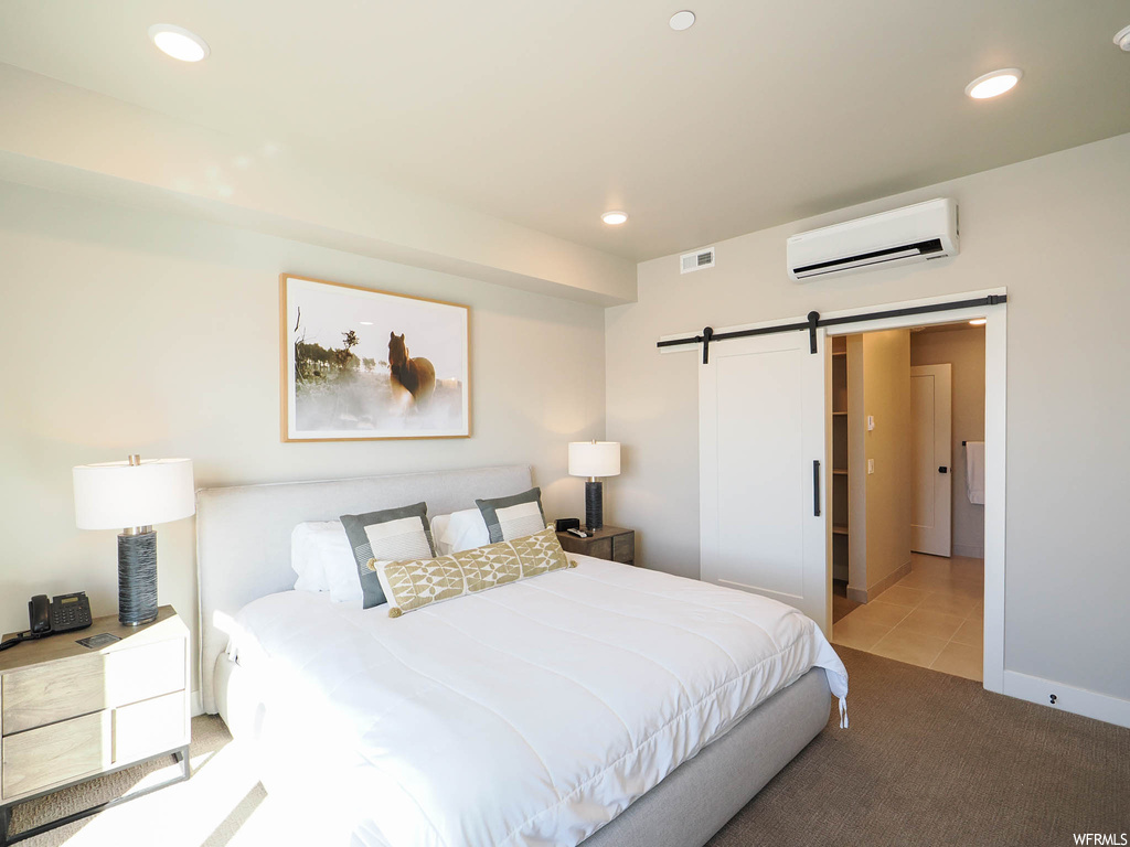 Carpeted bedroom with a wall mounted AC and a barn door