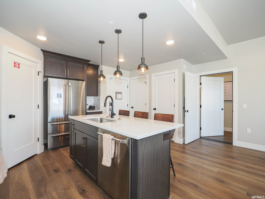 Kitchen featuring dark hardwood / wood-style floors, sink, a kitchen island with sink, and stainless steel appliances