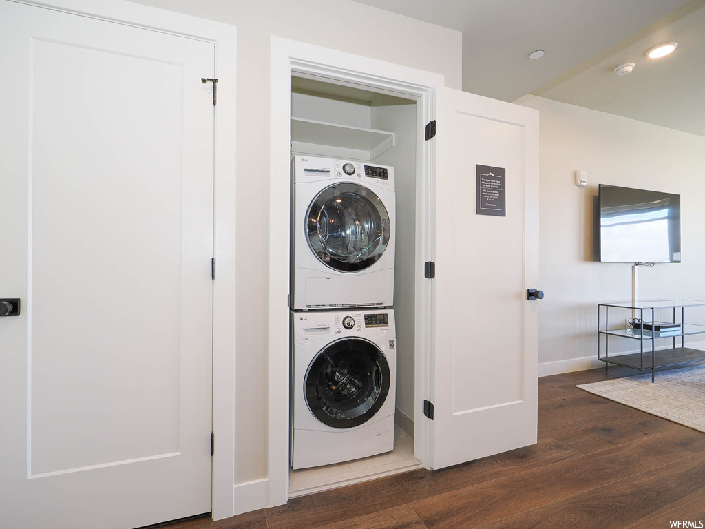 Washroom featuring dark hardwood / wood-style flooring and stacked washer and dryer