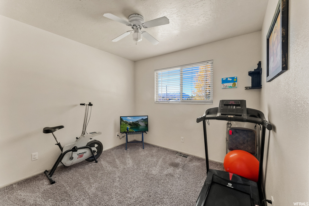 Workout area with ceiling fan and light carpet