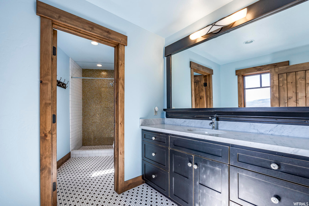 Bathroom featuring tiled shower, vanity, and tile floors
