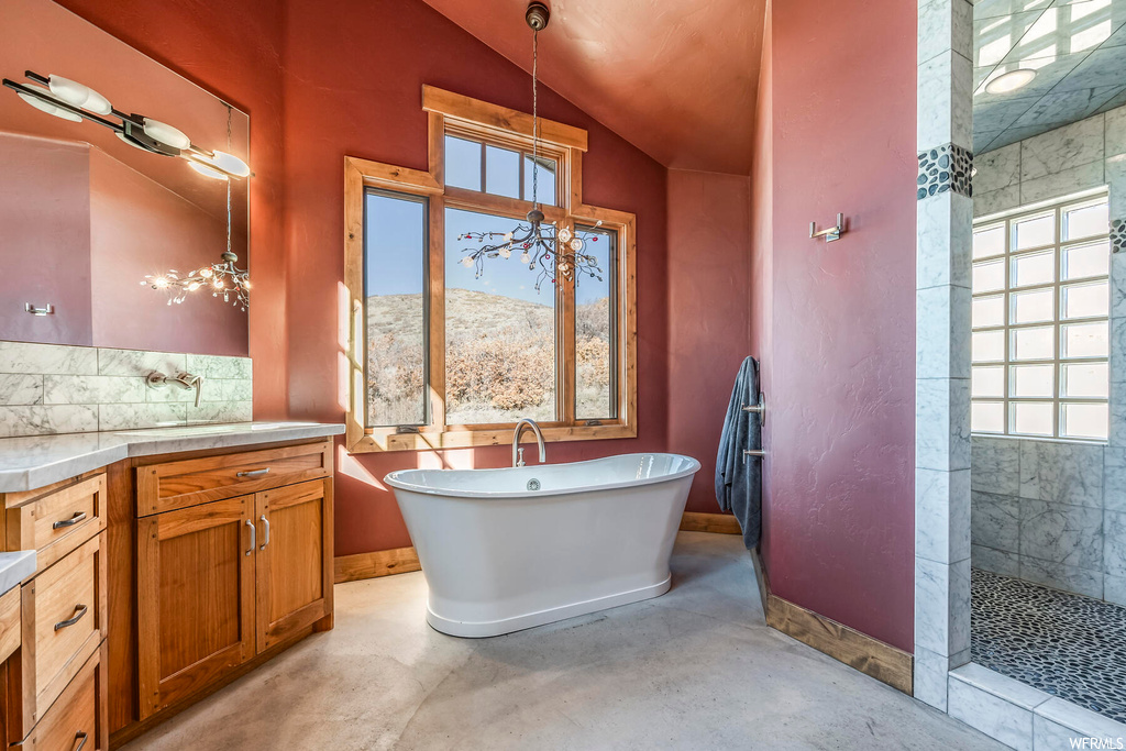 Bathroom featuring vanity, a mountain view, concrete floors, lofted ceiling, and separate shower and tub