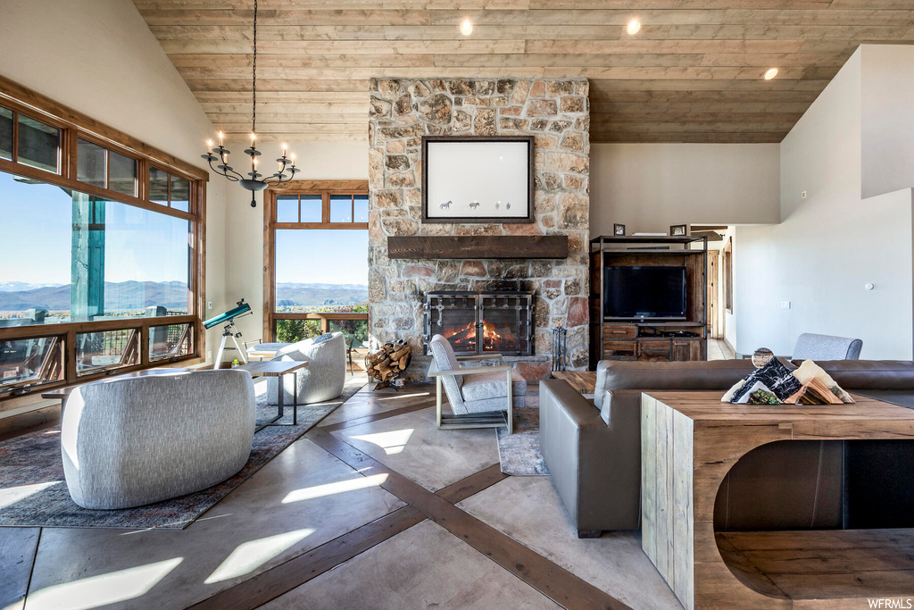 Living room featuring an inviting chandelier, a fireplace, a mountain view, high vaulted ceiling, and wooden ceiling