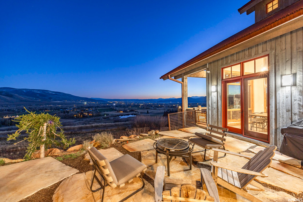 Patio terrace at dusk featuring a fire pit and a mountain view