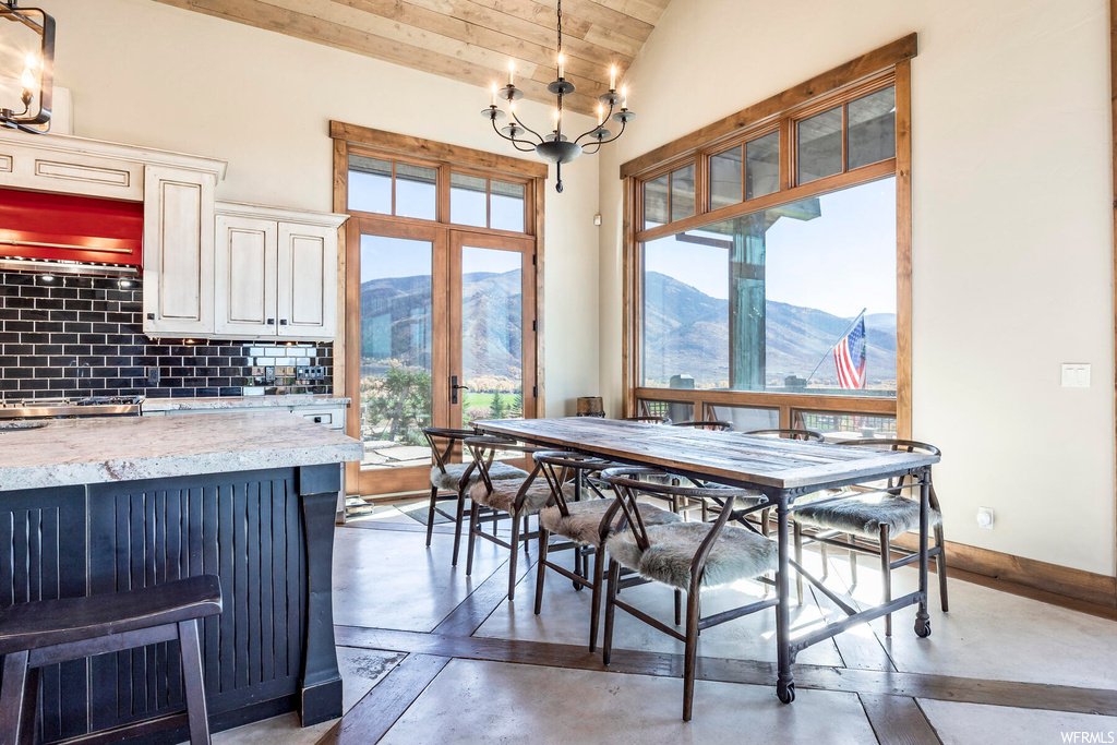 Dining space with a mountain view, concrete flooring, an inviting chandelier, and lofted ceiling with beams