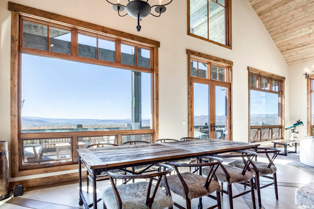 Dining space with wood ceiling, an inviting chandelier, a mountain view, high vaulted ceiling, and french doors