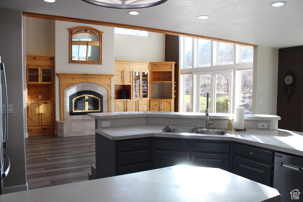 Kitchen featuring a tile fireplace, sink, gray cabinets, stainless steel dishwasher, and dark hardwood / wood-style floors