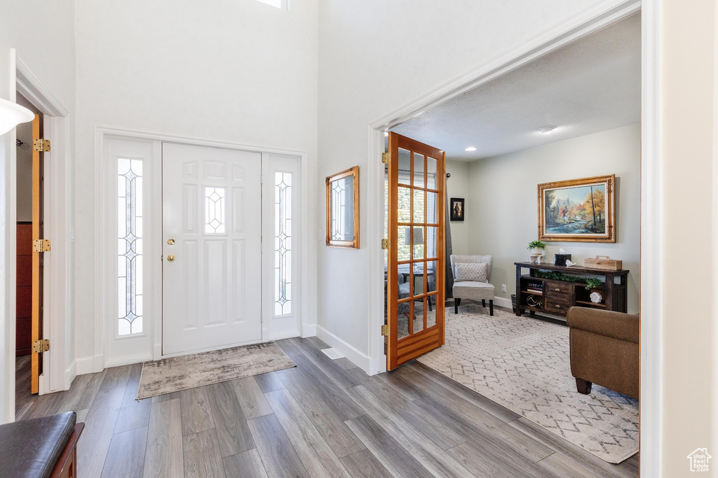 Entrance foyer with light wood-type flooring, a wealth of natural light, and a high ceiling