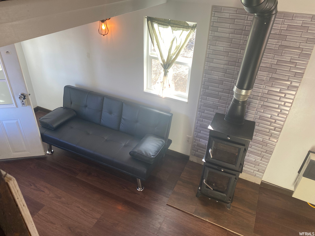 Living area featuring a wood stove, dark hardwood / wood-style flooring, and brick wall