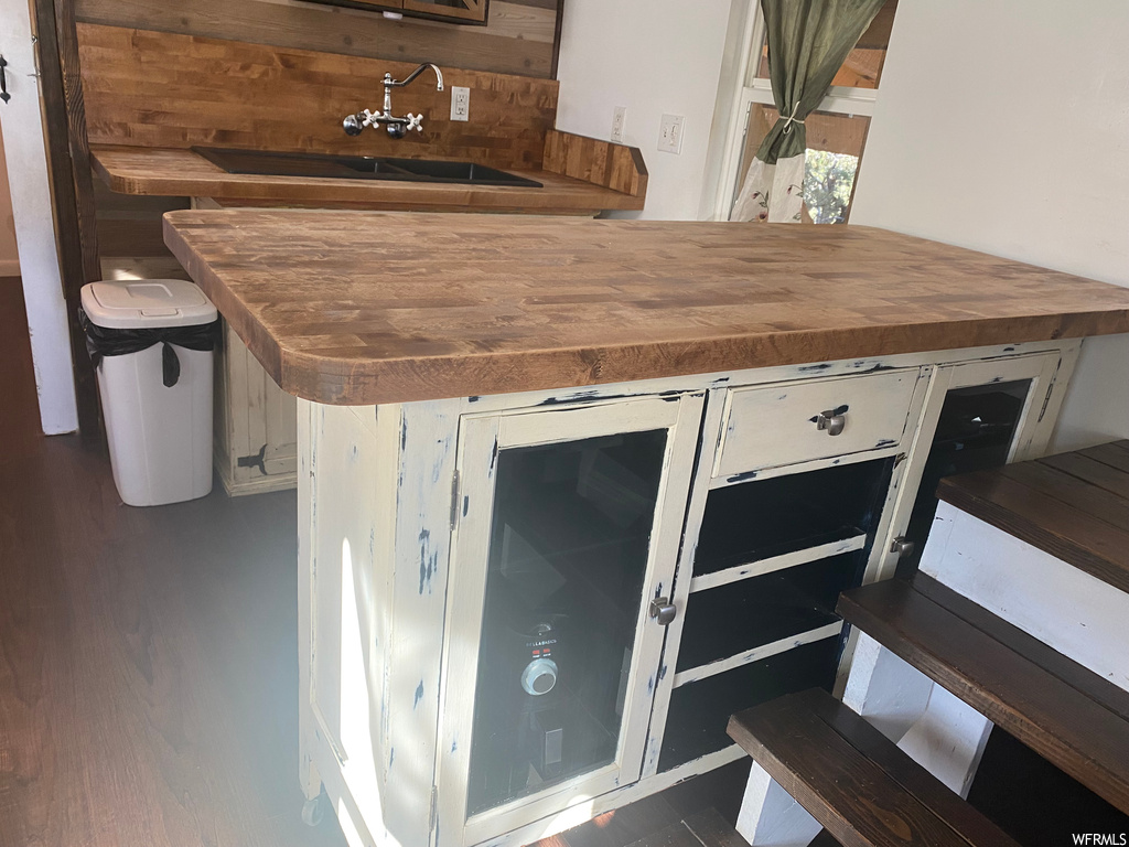 Interior space with wooden counters, white cabinets, and sink