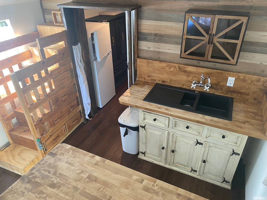 Kitchen with sink, wooden walls, and white fridge