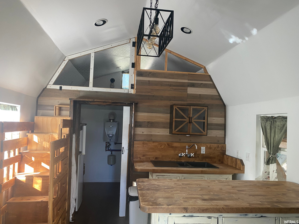 Kitchen featuring sink, lofted ceiling, wood walls, and wood counters