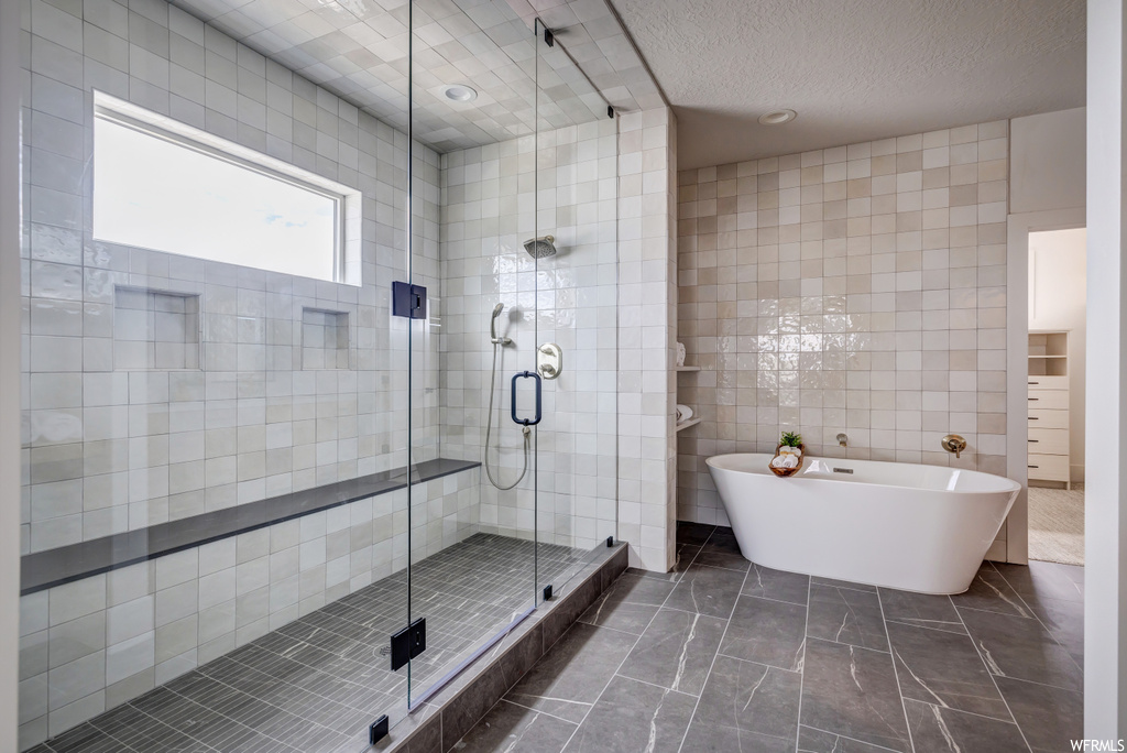 Bathroom with tile floors, tile walls, and independent shower and bath
