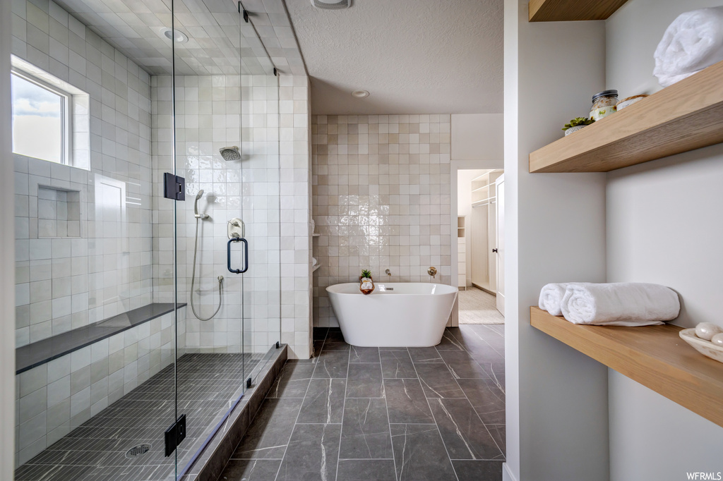 Bathroom featuring tile walls, shower with separate bathtub, and tile flooring