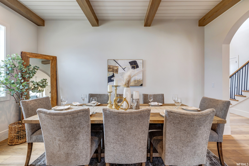 Dining space with beam ceiling and light hardwood / wood-style flooring