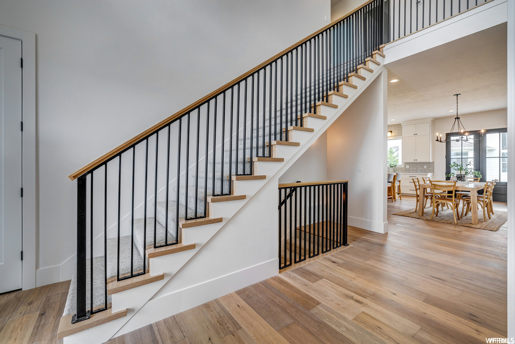 Stairs featuring an inviting chandelier and light hardwood / wood-style flooring