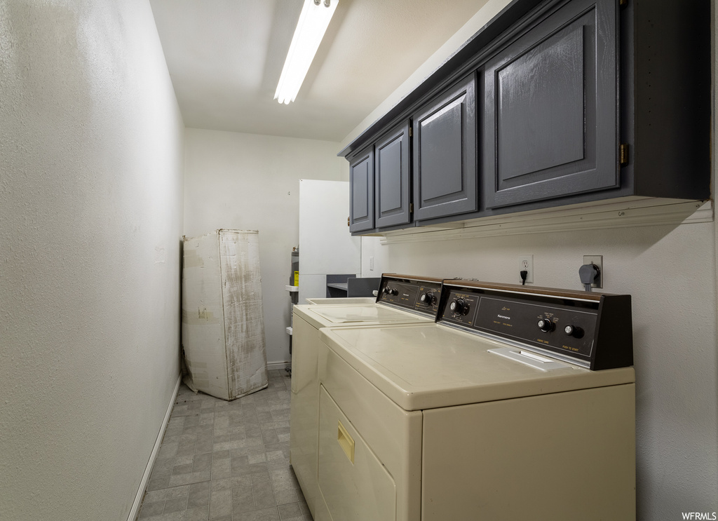 Laundry area featuring electric dryer hookup, washing machine and clothes dryer, light tile floors, and cabinets