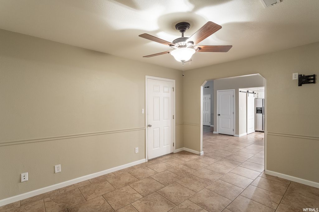 Tiled spare room featuring ceiling fan