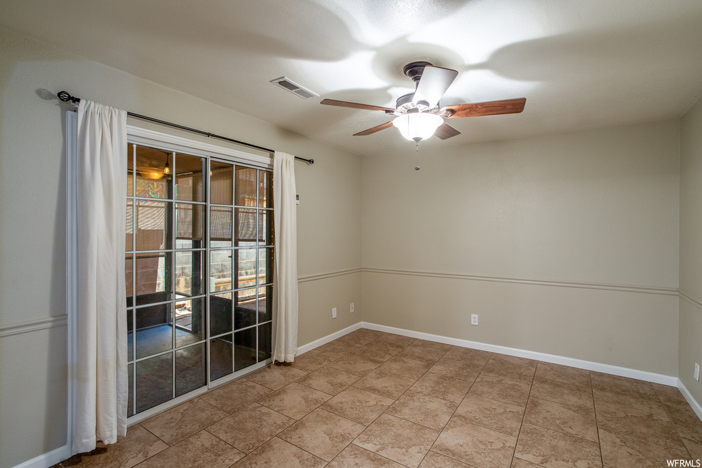 Spare room with ceiling fan and light tile floors