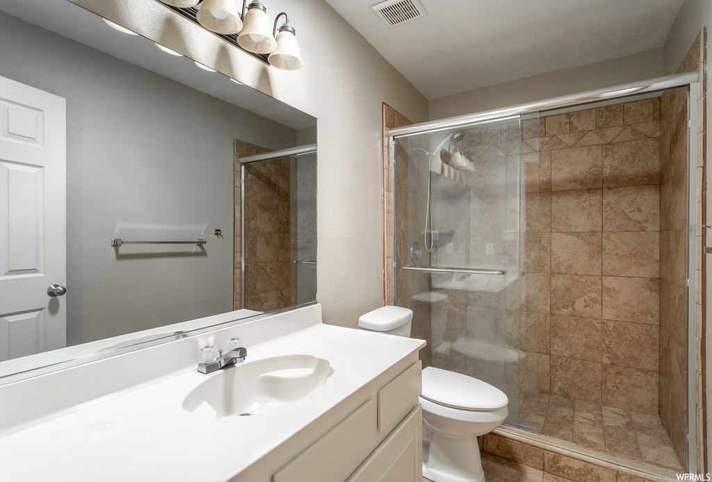 Bathroom with an enclosed shower, large vanity, and toilet