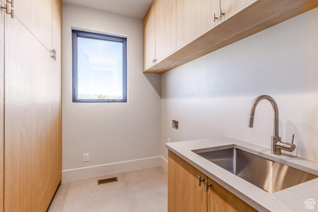 Interior space with light brown cabinetry, light tile patterned floors, and sink