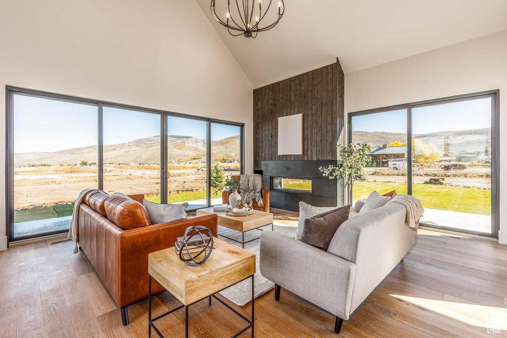 Living room with light wood-type flooring, a chandelier, a mountain view, and high vaulted ceiling