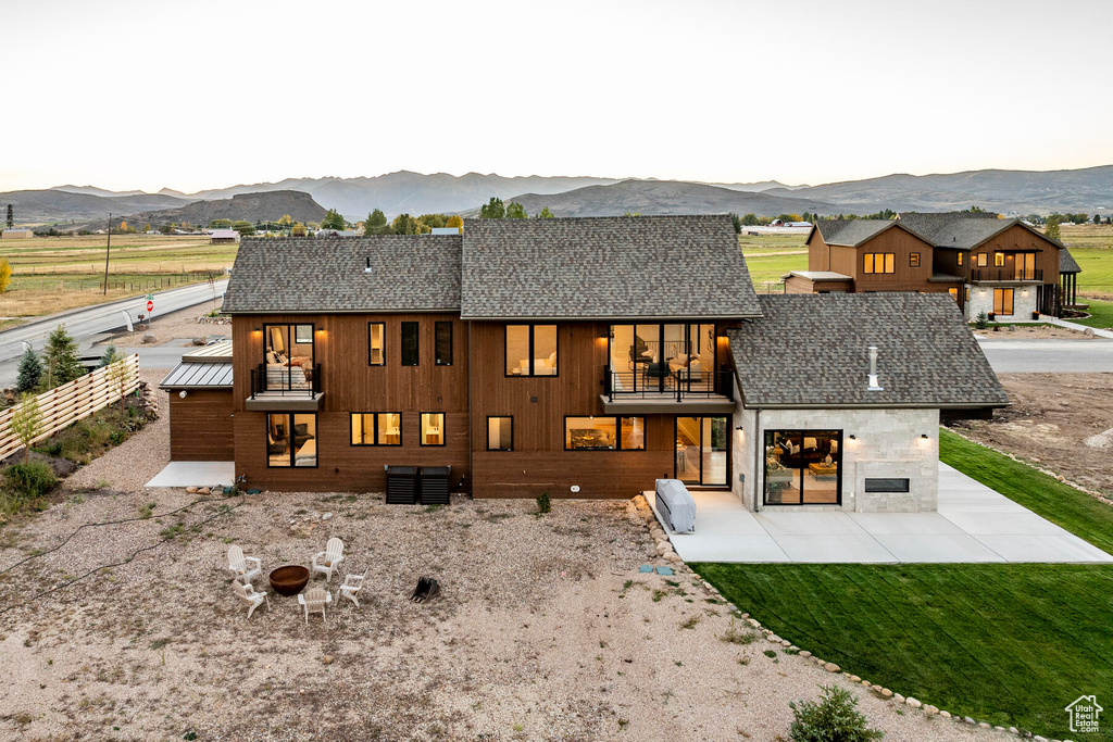 Back of property with a mountain view, a patio area, a balcony, a yard, and a garage