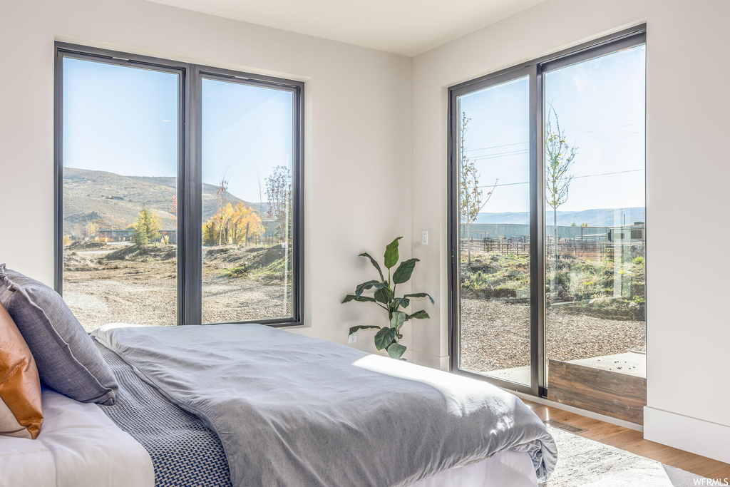 Bedroom featuring light hardwood / wood-style floors, a mountain view, and access to outside