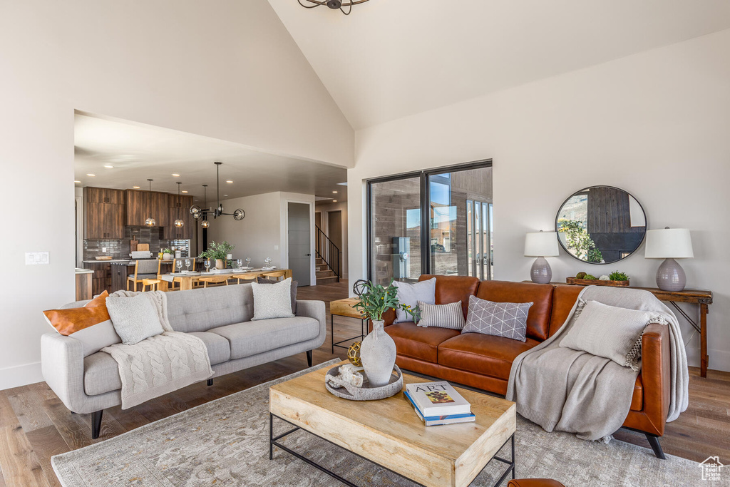 Living room featuring light hardwood / wood-style flooring, a chandelier, and high vaulted ceiling