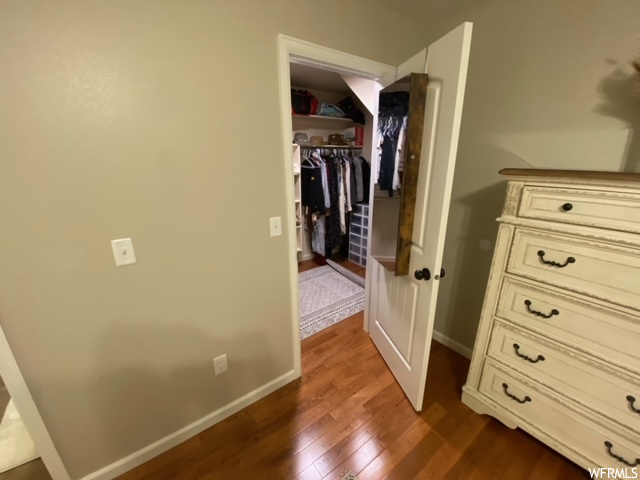 Unfurnished bedroom with a walk in closet, dark wood-type flooring, and a closet